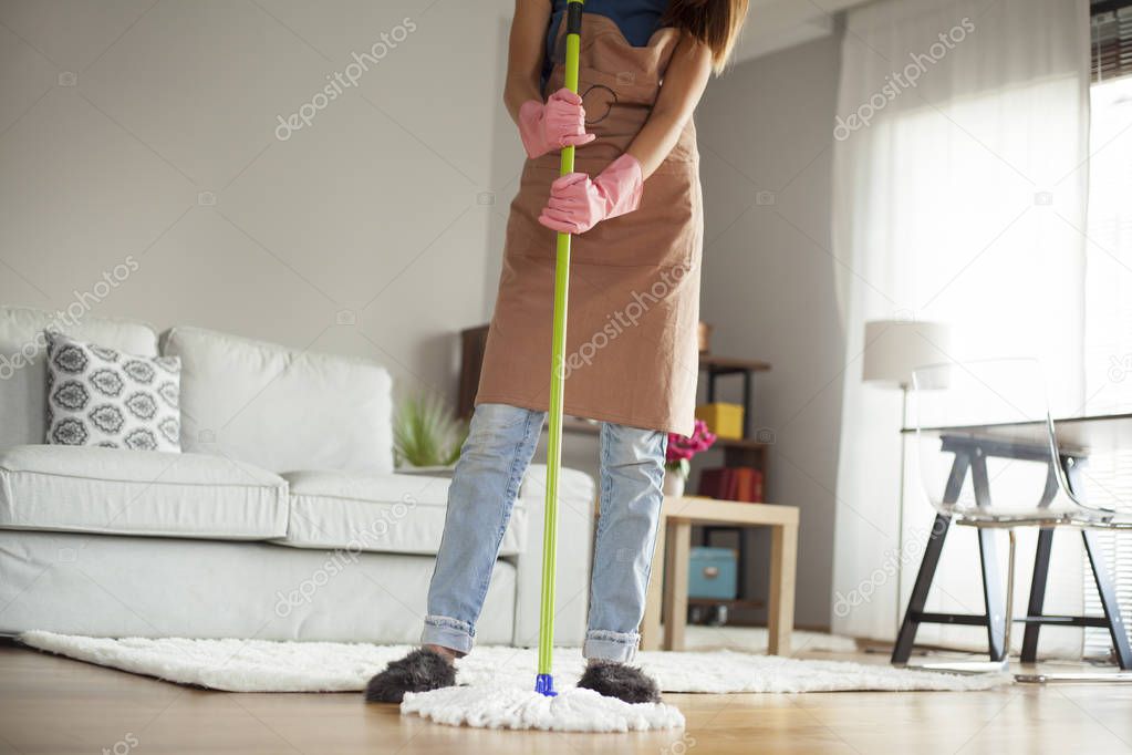 Young woman cleaning floor in room