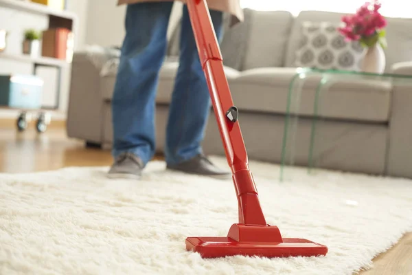 Man schoonmaak tapijt met een stofzuiger op kamer — Stockfoto