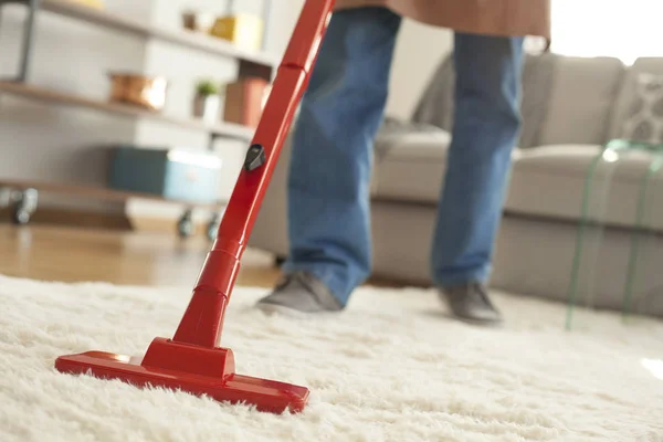 Man schoonmaak tapijt met een stofzuiger op kamer — Stockfoto