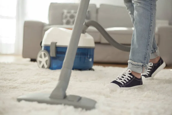 Vrouw schoonmaken tapijt met een stofzuiger in de kamer — Stockfoto