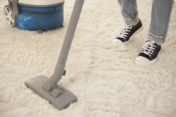Kvinna rengöring matta med en dammsugare i rummet — Stockfoto
