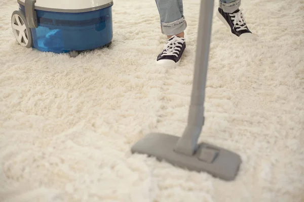 Vrouw schoonmaken tapijt met een stofzuiger in de kamer — Stockfoto