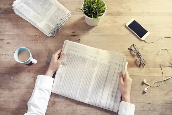 Lectura de periódico en mesa de madera — Foto de Stock