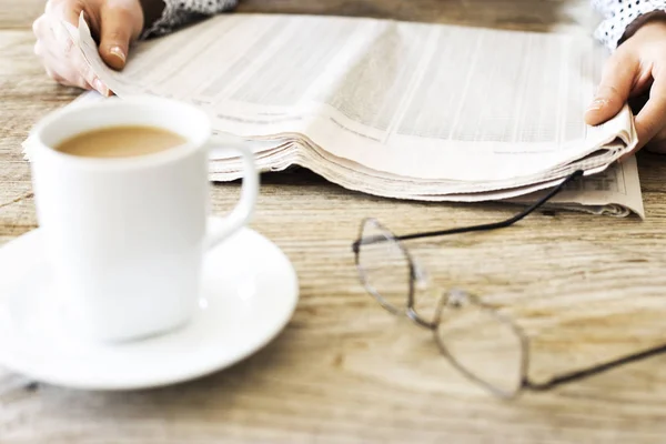 Lectura de periódico en mesa de madera — Foto de Stock