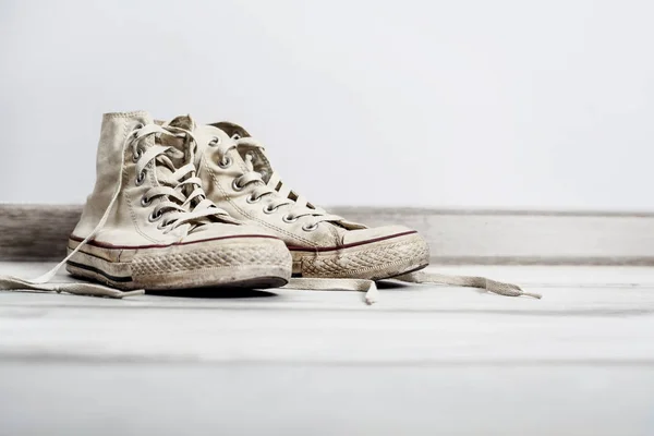 Velhos tênis brancos no fundo de madeira — Fotografia de Stock