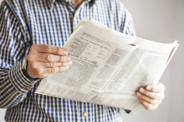 Hombre leyendo periódico sobre fondo gris — Foto de Stock