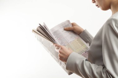 Beyaz arka planda gazete okuyan genç bir kadın.