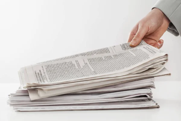 Ženská ruka drží noviny na stůl — Stock fotografie