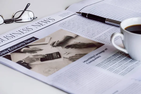 Periódico con anteojos sobre mesa blanca — Foto de Stock