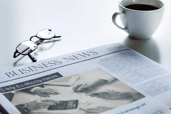 Periódico con anteojos sobre mesa blanca — Foto de Stock