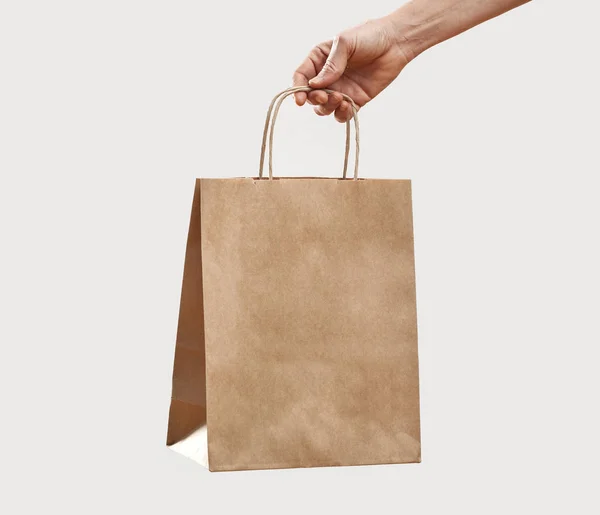 Mujer sosteniendo papel bolsa de compras sobre fondo gris — Foto de Stock