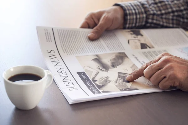Hombre leyendo el periódico en la mesa — Foto de Stock