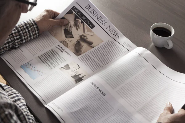 Hombre mayor leyendo el periódico en la mesa —  Fotos de Stock