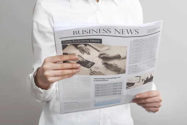 Empresaria leyendo periódico sobre fondo gris — Foto de Stock