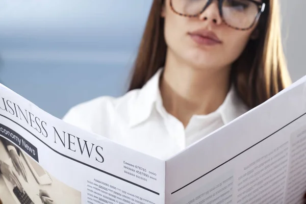 Empresaria leyendo periódico sobre fondo gris — Foto de Stock