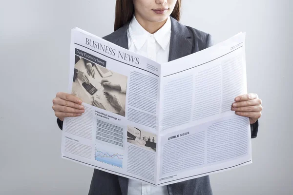 Empresaria leyendo periódico sobre fondo gris — Foto de Stock