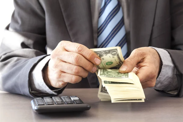 Бизнесмен держит доллар на столе — стоковое фото