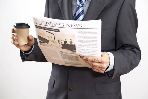 Businessman reading newspaper on gray background — Stock Photo, Image