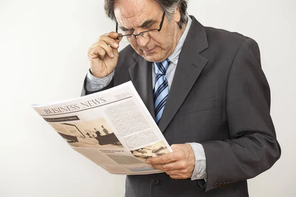 Geschäftsmann liest Zeitung auf grauem Hintergrund — Stockfoto