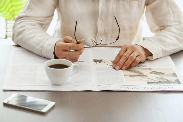 Hombre leyendo el periódico en la mesa — Foto de Stock