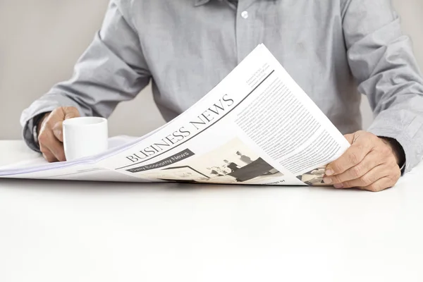 Hombre leyendo el periódico en la mesa — Foto de Stock