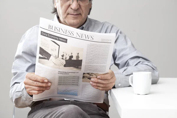 Homem sênior lendo jornal em fundo cinza — Fotografia de Stock
