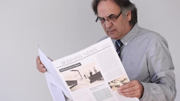 Hombre mayor leyendo periódico sobre fondo gris — Vídeos de Stock