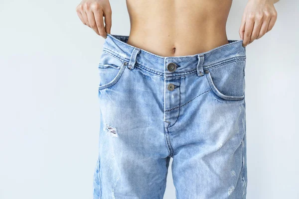 Hmotnost ztráta žena s jean na šedém pozadí — Stock fotografie