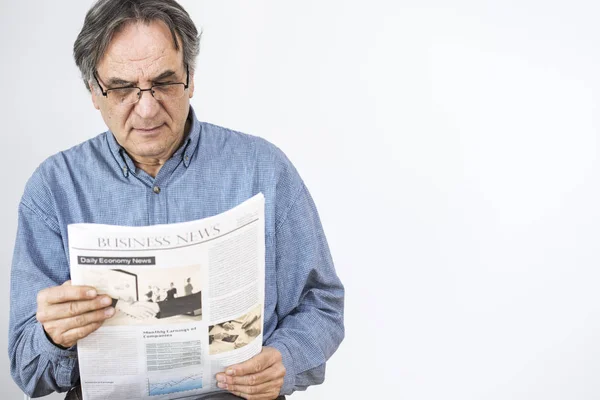 Homem sênior lendo jornal em fundo cinza — Fotografia de Stock