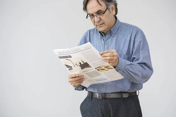 Homem sênior lendo jornal em fundo cinza — Fotografia de Stock