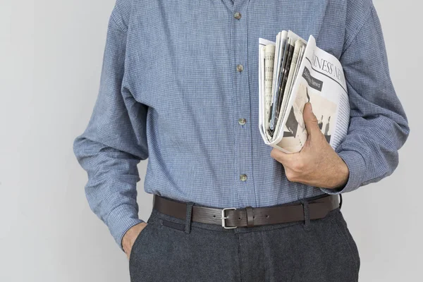 Hombre mano sosteniendo la lectura de periódico sobre fondo gris — Foto de Stock
