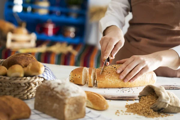 Mains féminines coupant du pain frais — Photo