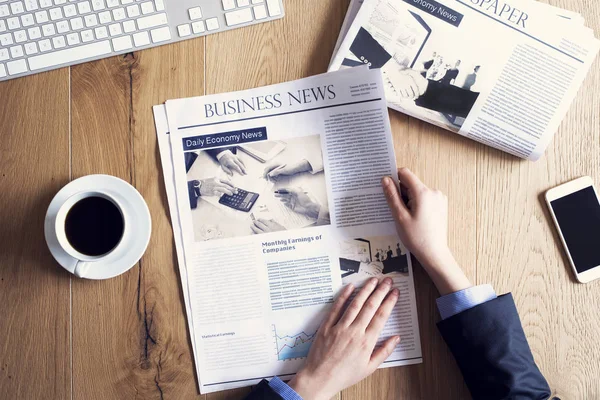 Leer el periódico en el escritorio — Foto de Stock