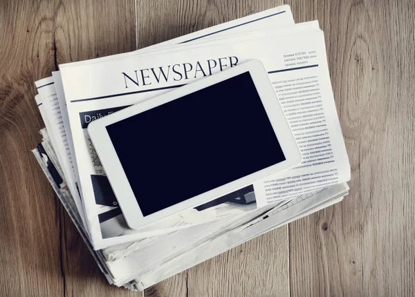 Newspaper with digital tablet on wooden table