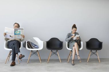 Okuma gazete ve dijital tablet kullanan kadın adam