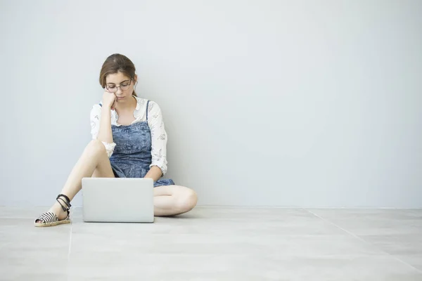 Молода дівчина використовує ноутбук на підлозі — стокове фото