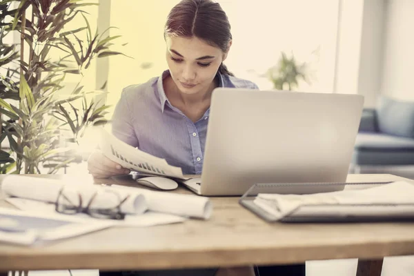Vrouw met behulp van de laptop terwijl u werkt — Stockfoto