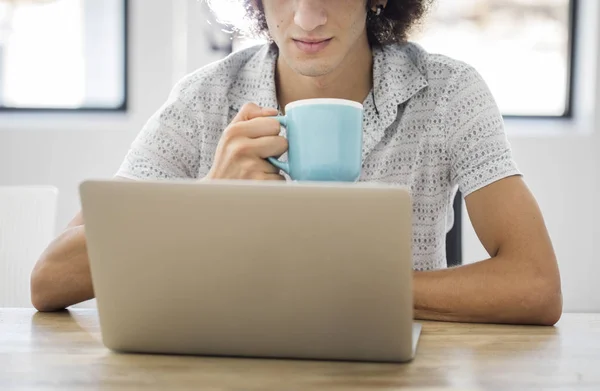 Junger Mann arbeitet mit Computer und trinkt Kaffee — Stockfoto