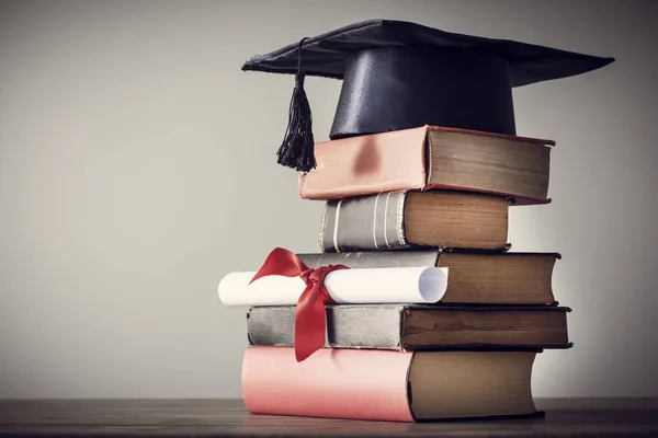 Chapéu de graduação e diploma com livro na mesa — Fotografia de Stock