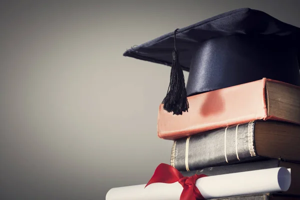 Avläggande av examen hatt och diplom med boken på bordet — Stockfoto