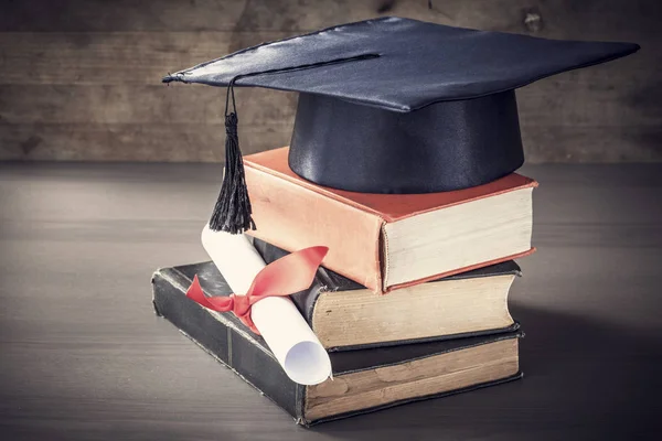 Avläggande av examen hatt och diplom med boken på bordet — Stockfoto