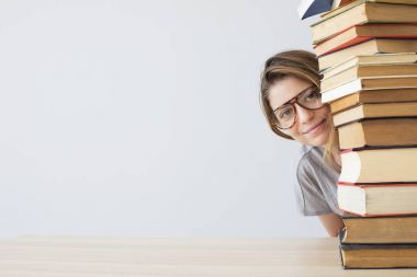 Bir yığın kitap ile mutlu öğrenci