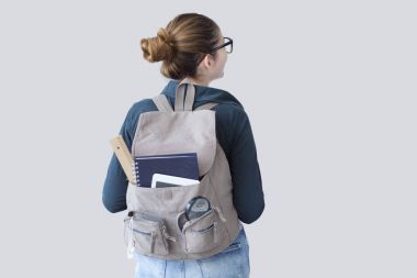 Gri arka plan üzerinde sırt çantası ile öğrenci