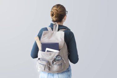 Gri arka plan üzerinde sırt çantası ile öğrenci