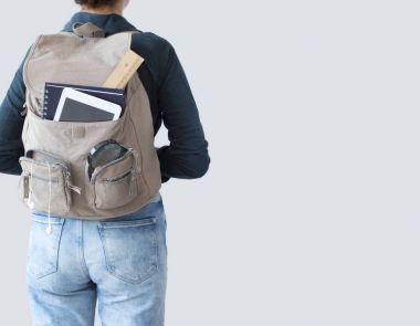 Gri arka plan üzerinde sırt çantası ile öğrenci