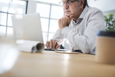 Masa üstünde laptop üzerinde çalışıyor