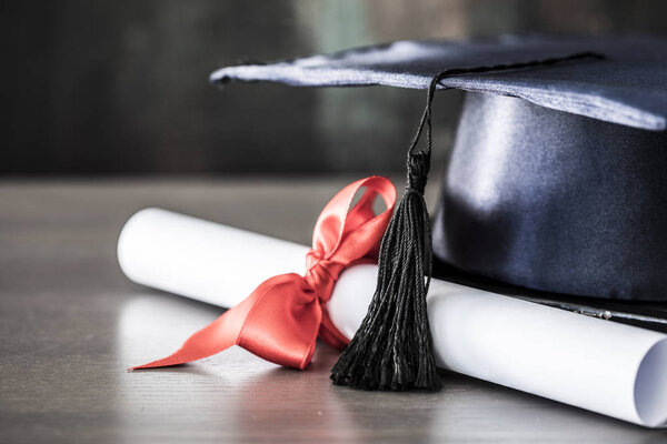 Graduation hat and diploma on table