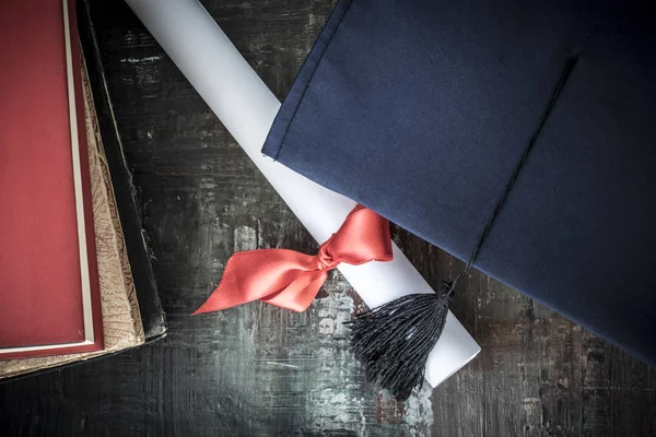 Graduation hat and diploma on table — Stock Photo, Image