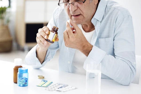 Old man taking a pill