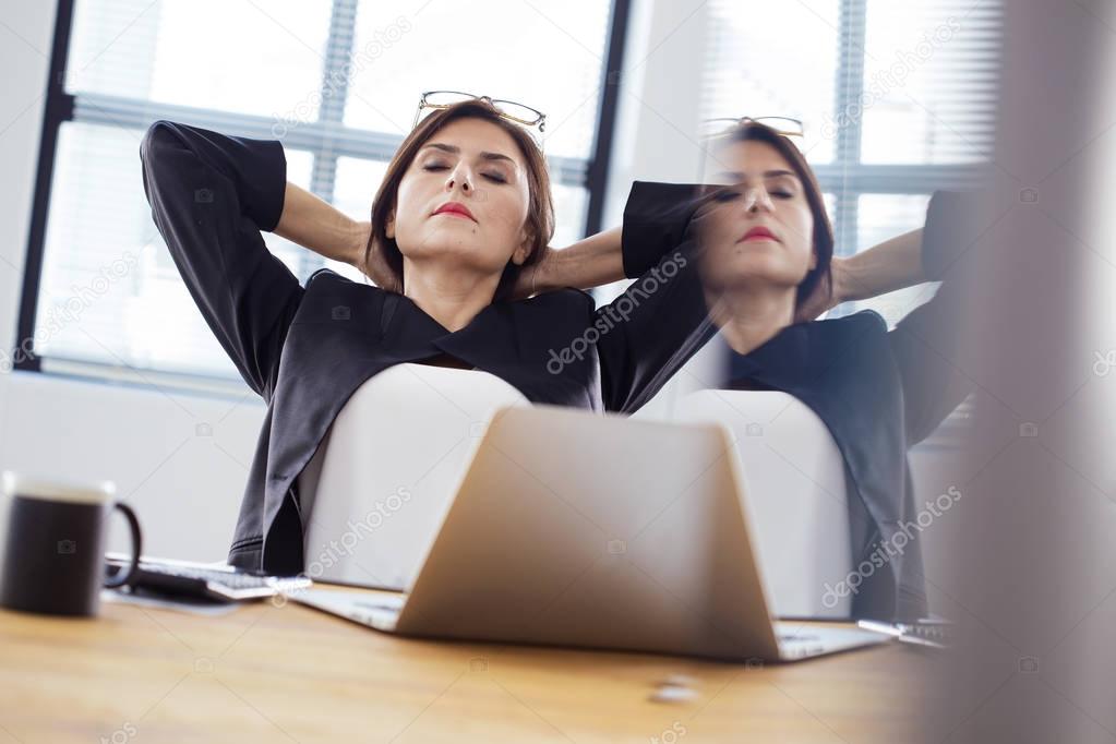 Tired businesswoman stretching in office